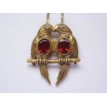 A 14ct gold, diamond and garnet pendant necklace, in the form of a pair of lovebirds on a perch,