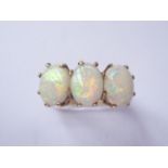 A three-stone opal dress ring, each cabochon of approximately .78ct, crown-held above a 9ct gold