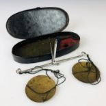 A Georgian set of pocket steel and brass coin / sovereign scales, within a Japanned oval case