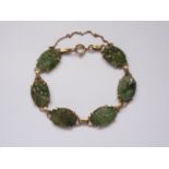 An antique jade and yellow metal bracelet, comprising oval-shaped jade plaques, carved and