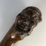 A 19th century carved root bulb walking cane, the pommel modelled as the grinning head of a man,
