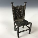 A Victorian silver miniature chair, having repousse moulded back depicting a putto playing a