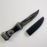 A Victorian sgian dubh, the ebonised grip having electroplate mounts and paste-set pommel, the blade
