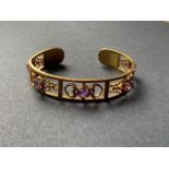 A silver-gilt openwork bangle, the face claw-set with round-cut amethysts flanked by reticulated