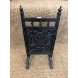 A carved wooden fire screen