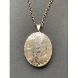 An uncommonly large silver locket on chain, of oval section, with foliate engraved face, 40.5g