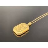 A 9ct gold locket on chain, of rectangular section with canted corners and engraved foliate
