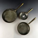 A graded set of tinned copper pans with brass handles