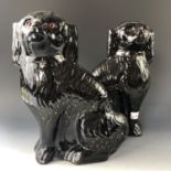 A pair of Victorian Staffordshire type earthenware hearth dogs / spaniels, black glazed and gilt