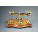 A set of Victorian brass postal scales and weights on a walnut base, 21 x 12 x 21 cm high