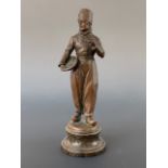 A late 19th / early 20th century bronzed statuette of a Dutch fisherman holding a pipe and basket,