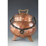 An early 20th Century Arts and Crafts copper cauldron and cover, of oblate from with squat