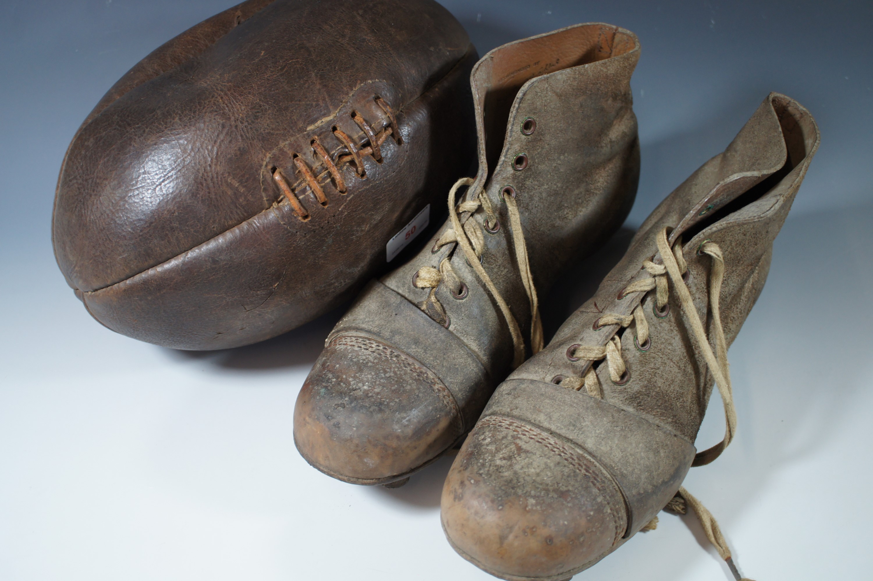 A vintage leather rugby ball and boots