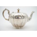 An early Victorian silver tea pot, loosely of melon form, being lobed and engraved, and decorated