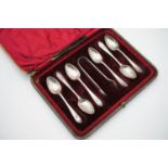 An Edwardian cased set of silver tea spoons and sugar tongs, feather pattern, with engraved monogram