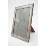 A 1920s silver photograph frame, with reed-and-ribbon pattern borders, and an oak easel back,