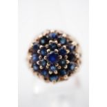 An early 1970s sapphire cocktail ring, claw-set in a tiered flower head cluster arrangement, with