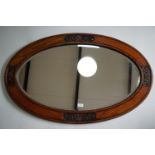 A large early 20th century carved oak oval wall mirror, 110 x 69 cm