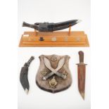 A Kukri and stand, together with a pair of mounted kukris and gurkha badges on a plaque etc