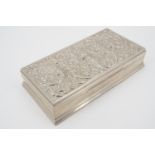 An Indian white metal table cigarette box, of rectangular section, the cover repousse moulded with