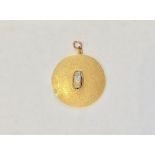 A contemporary high carat yellow metal and raw opal pendant, of discus shape, textured and centrally