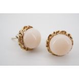 A pair of peach jade and yellow metal stud earrings, having a central polished cabochon, set