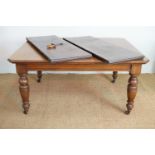 A late Victorian oak extending dining table with two leaves