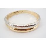 A contemporary high-carat two colour yellow and precious white metal hinged bangle, of double