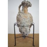 A wreck-recovered ancient Graeco-Roman amphora, encrusted and in a wrought iron stand, approx 90 cm