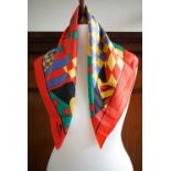 A Lonchamp silk neck square / scarf, the pattern incorporating jockey hats and silks, 50 x 50 cm