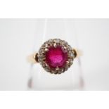 A vintage diamond and ruby flower head cluster dress ring, having a central round-cut claw-set