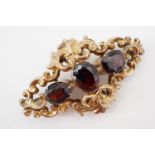 A Victorian yellow-metal and garnet brooch, having three oval-cut garnets, the central of