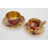 Two Royal Worcester fruit study cups with associated saucers, hand-painted respectively by Horace