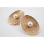 A pair of high carat yellow metal and pearl ear clips, each of oval section and dished form,