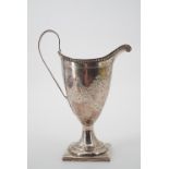 A George III silver footed cream jug, of helmet form raised over a square plinth, with beaded rim,