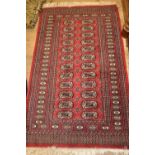 Near pair of Pakistan Bokhara rugs, each with a twin row of gols on a wine ground with borders,