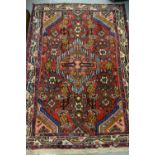Two small Hamadan rugs with centre medallion and multiple borders on a red ground,