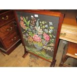 Mahogany fire screen inset with a floral woolwork panel