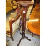 Reproduction carved mahogany torchere with a spiral turned column and tripod base