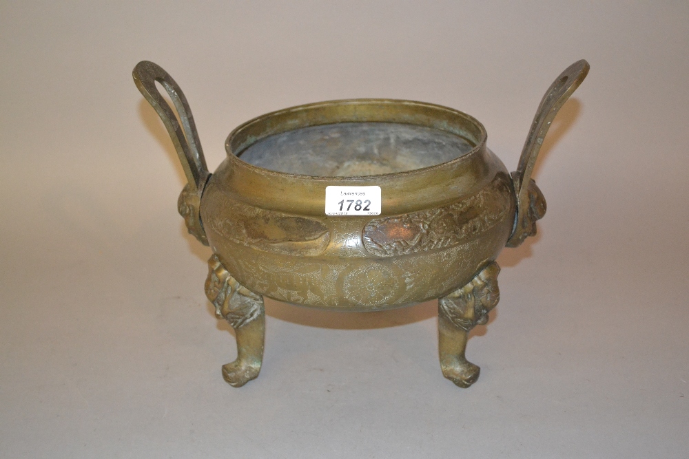 Oriental patinated bronze two handled incense burner, raised on mask head supports