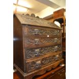 Late 19th Century carved oak bureau, the fall front above four graduated drawers with mask head