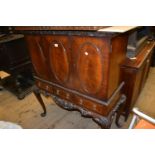 Reproduction mahogany cocktail cabinet with oval panelled doors above three drawers raised on carved