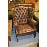 20th Century brown buttoned leather upholstered wing back armchair, raised on mahogany supports
