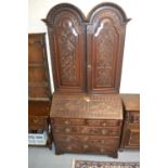 Carved oak bureau bookcase with a double dome two door top, above fall front enclosing fitted