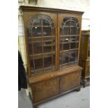 1930's Walnut bookcase with a moulded cornice above two arched glazed doors, above two panel doors