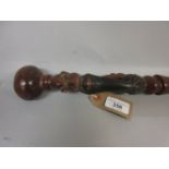 African hardwood walking cane, the handle carved with tribal faces