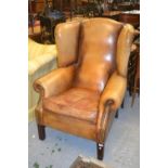 Reproduction mahogany tan leather upholstered wing back armchair on square moulded front supports