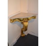 Pair of giltwood corner tables, each with flecked marble tops, a shallow frieze and single scroll