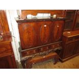 Reproduction mahogany cocktail cabinet with oval panelled doors above three drawers raised on carved