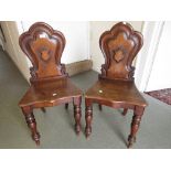 Pair of Victorian oak shield back hall chairs with panelled seats raised on turned front supports